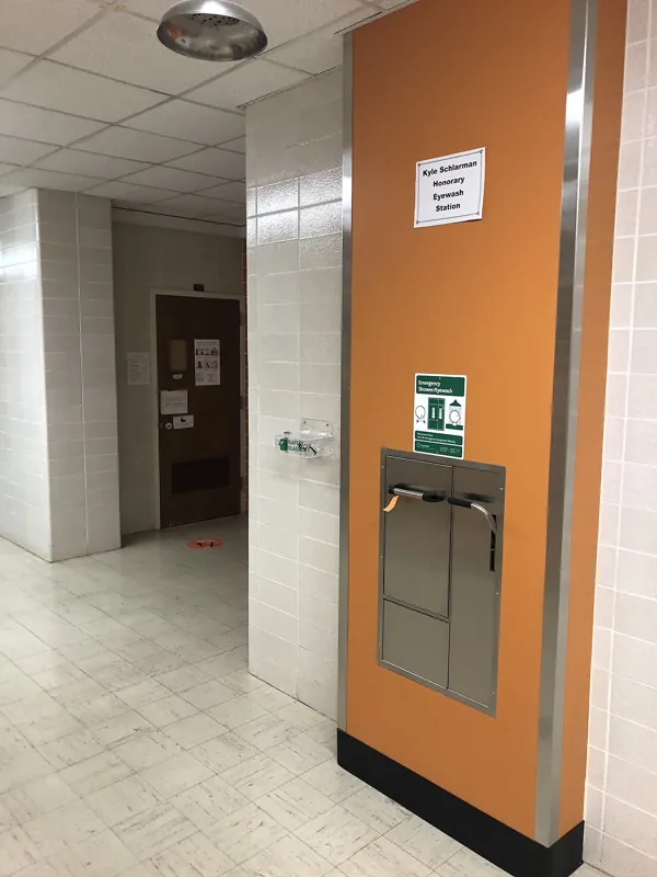 Estação de chuveiro e lava-olhos de emergência embutida na parede de um corredor