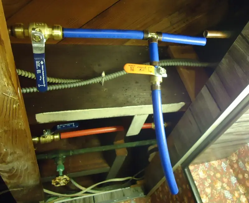 Tubos de PEX azul e vermelho instalados com conexões de latão